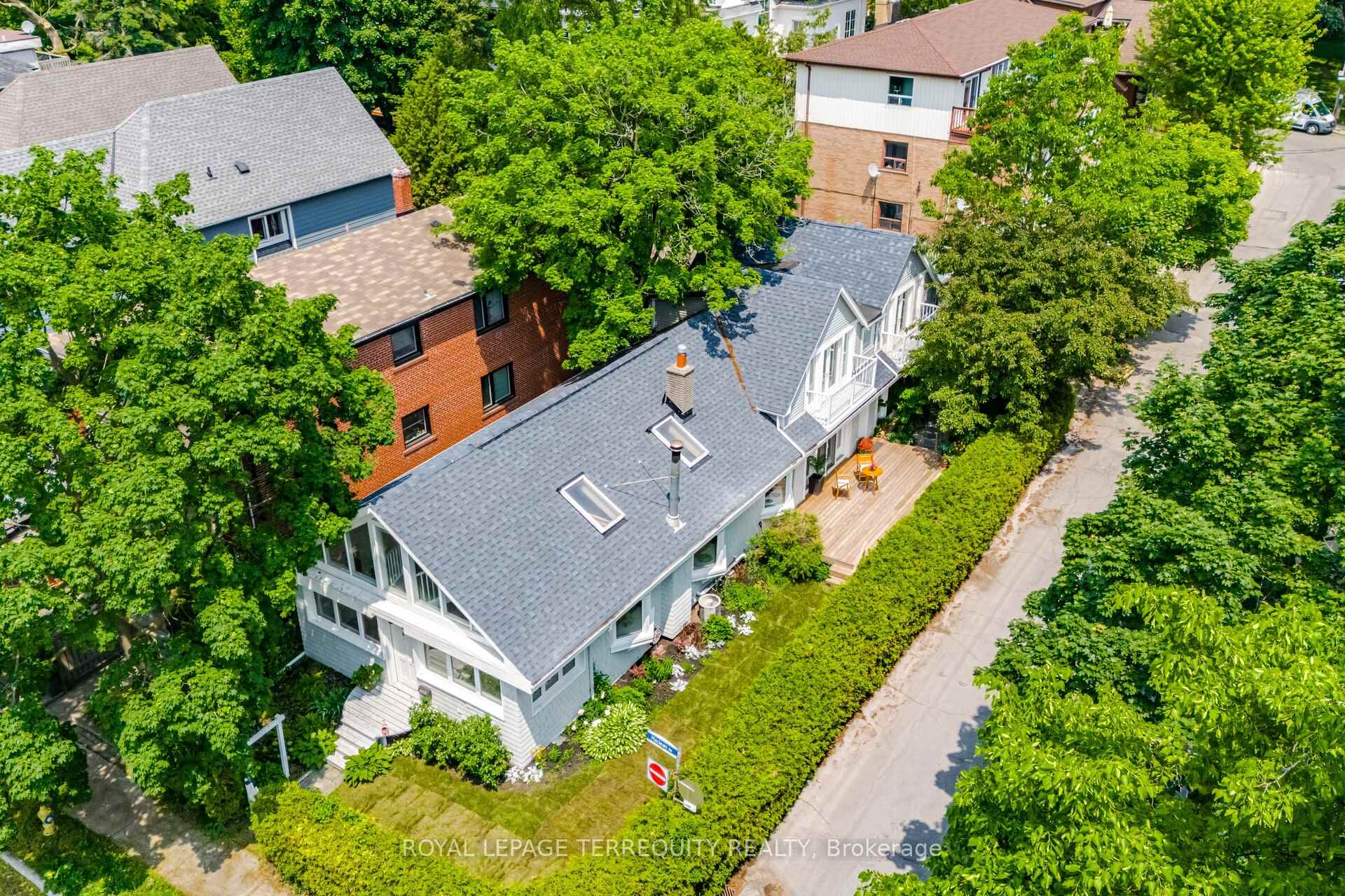 If you've walked through The Beaches along the boardwalk, you've likely noticed this soulful and distinctive home, but the real charm begins inside. Every room offers breathtaking views of Lake Ontario, with a design that embraces natural light, positive energy, and a comforting atmosphere that feels like a country home in the city. The front door opens to a bright office or study framed by garden and lake views. A ladder leads to a magical loft space ideal for reading, meditation, reflection, or imaginative play, with a charming pass-through overlooking the main living area. The open-concept living, dining, and kitchen space features cathedral wood ceilings, exposed beams, skylights, and three bay windows that bathe the space in natural light through every season. A wood-burning fireplace adds warmth and calm year-round. Beyond the kitchen is a cozy family room with built-in shelving, once used as an art studio. Upstairs, the second bedroom includes a vaulted dormer ceiling, three piece ensuite, a walkout balcony with lake views, and a colourful leaded glass pocket door. The spacious primary suite includes cathedral ceilings, a jetted soaker tub, a large walk-in closet, and French doors that open onto an oversized rooftop deck surrounded by mature trees for privacy and shade while still offering stunning views of the lake and boardwalk.A second staircase leads back to the main floor. There is a bathroom, laundry area, wet bar (easily converted to a kitchenette), and a third oversized bedroom with two entrances and a garden walkout, ideal as a private suite. The unfinished basement offers generous storage. Located across from Balmy Beach, this home is in park heaven, with four nearby parks, numerous trails, and easy access to Kew Beach, downtown Toronto, the QEW, DVP, TTC, and a vibrant stretch of Queen Street filled with one of a kind shops, cafés, and boutiques. This is a unique home you won't want to miss.