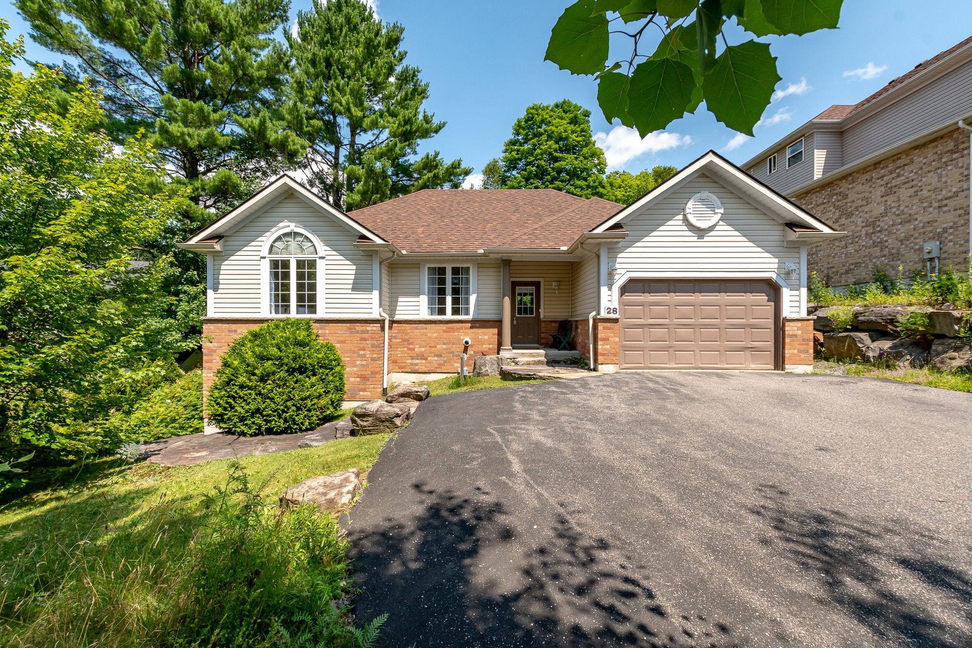 28 KIRBYS Way Huntsville, Ontario Set back from the road behind a mature tree line, this charming bungalow offers a rare sense of privacy in a peaceful, picturesque setting. Step inside through the generous foyer and discover a bright, airy living room that flows effortlessly into the open-concept kitchen and dining area, an ideal layout for casual family time or entertaining guests. The kitchen provides plenty of counter space, making it both functional and inviting, while the dining area opens directly onto a large deck, perfect for enjoying meals outdoors. Conveniently located near the bedrooms, the laundry closet adds ease to everyday routines. The primary suite serves as a private haven, featuring a walk-in closet and a well-appointed three-piece ensuite designed for comfort. Two additional bedrooms offer cozy accommodations for family or visitors and share access to a spacious four-piece guest bath. Downstairs, the expansive unfinished basement presents a world of potential, complete with a bathroom rough-in and a cold cellar, ideal for creating a custom space to suit your lifestyle, whether that means a fitness studio, home office, or media room. Enjoy the comfort of full municipal services, including natural gas heating and air conditioning, on-demand hot water, and town water and sewer. Located just minutes from downtown, this home offers the perfect balance of quiet living and urban convenience. If you're looking for a well-appointed home with space, privacy, and flexibility, this bungalow is a must-see.