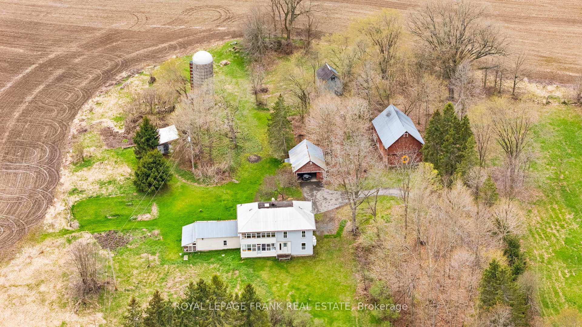 A peaceful rural escape awaits you in Seeleys Bay, nestled on approx. 70 scenic acres. This two-storey farmhouse offers a wonderful blend of comfort, character, and outdoor freedom. Step onto the inviting front porch and feel instantly at ease this is a place where mornings begin with coffee and birdsong. Inside, the main level welcomes you with wood floors, an expansive, bright, eat-in kitchen ideal for casual meals or catching up with family. The main principal room has beautiful hardwood floors, is large enough to host the whole extended family for dinner, or set it up as a large living  room? Ambiance abounds with a wood stove and adjacent cozy den/living room/study- a quiet place to unwind, relax with a good book or great conversations. There is also a rough-in for a small bathroom. The sunroom and convenient main floor laundry adds everyday ease. The huge wall to wall windows bring in the sunshine and serenity of the outdoors Upstairs, there are three comfortable bedrooms, a fourth or den, two bathrooms, that could serve creative space, or an extra bedroom. Another light-filled sunroom on this level offers picturesque views and a tranquil spot to recharge. It could also be your home office or studio! Outside, theres room to roam meadows, mature trees, trails, fields to grow, several  useful outbuildings, (a barn, chicken coops, drive shed, silo). Whether you're dreaming of gardens, hobby farming, or just breathing in fresh country air, this property offers a true connection to nature. A detached garage provides great storage for tools, toys, or weekend projects. This home has been filled with laughter and love and offers the kind of peace and privacy that's becoming harder to find. Whether you're settling in full-time or searching for a weekend getaway, this special property is ready to welcome you home. The farmable acreage has been maintained by a local farmer and used to grow hay, soybeans, corn and oats. Back Deck is approx 27'4" (8.35 m) x 7'3"(2.23 m)